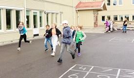 Barn springer på en skolgård medan föräldrar tittat på