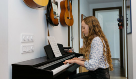 En högstadieelev sitter vid ett piano
