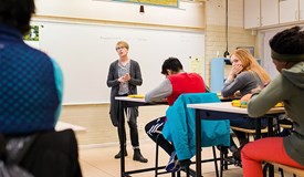 En lärare står vid whiteboardtavlan och undervisar en högstadieklass