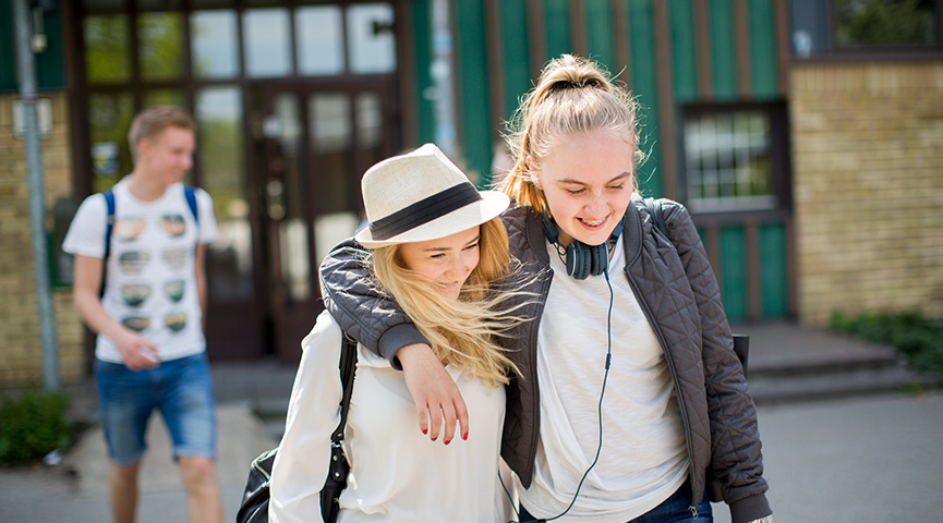 Två elever går bredvid varandra på en skolgård