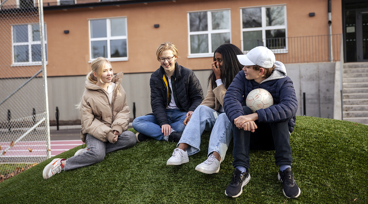 Elever sitter utanför en skola