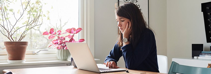 En gymnasieelev sitter hemma och studerar vid laptop