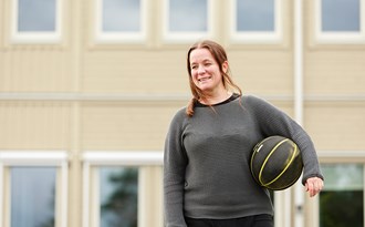 En idrottslärare står på skolgården med en basketboll